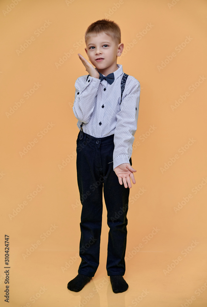 Portrait of a cute 10 years old schoolboy boy on a beige background. Standing straight at full height, Showing emotions, talking. Portrait of a cute 10 years old schoolboy boy on a beige background. Standing straight at full height, Showing emotions, talking.