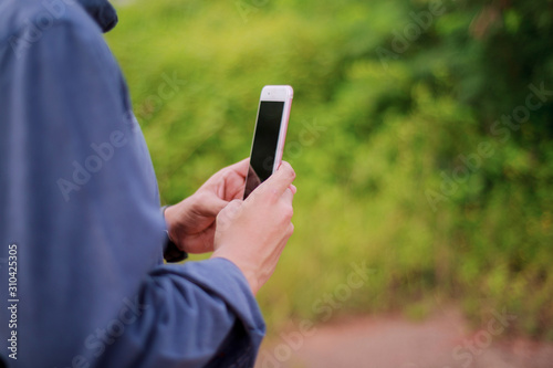 Crop shot view of Asian man's hands holding smart phone with blank copy space ,green background