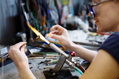 Woman artist making glass jewelry in her workshop