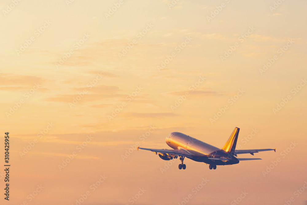 Airplane taking off and rising high in sunset sky
