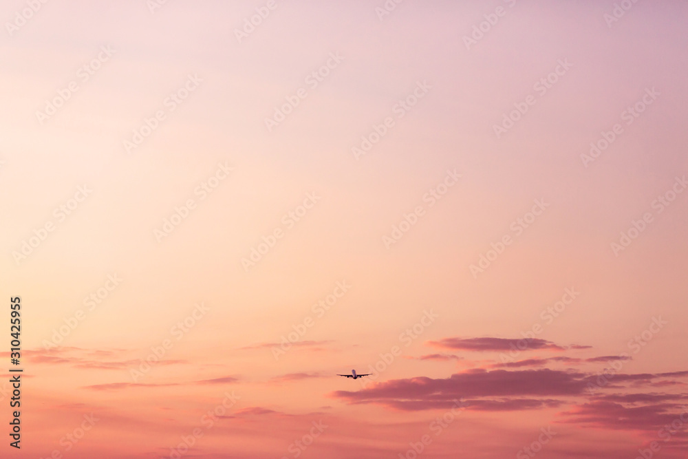 Fototapeta premium Airplane taking off and rising high in pink sunset sky