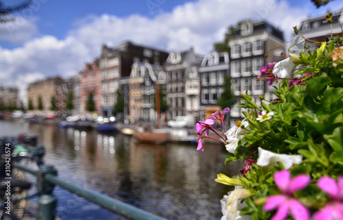Amsterdam,Holland,August 2019. Enchanting view of a canals of the historic center. The typical houses overlook the water, boats moored along the canal. Planters on railings and bikes. Sunny day. © Massimo Parisi
