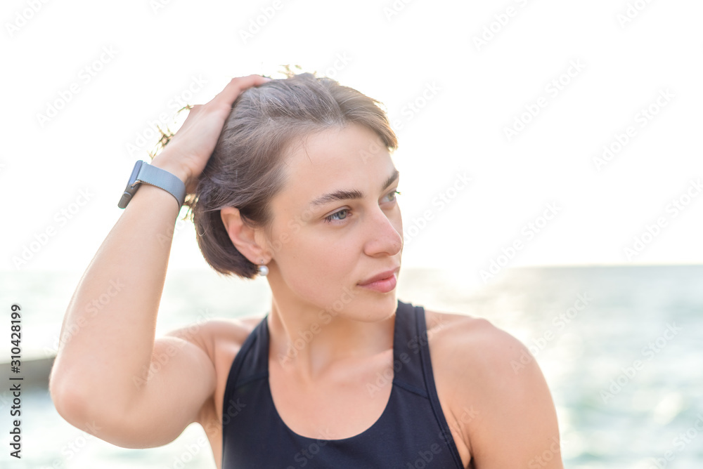 Young athletic beautiful girl with middle brown hair keeps her hair to back on backgroung of the sea Young athletic beautiful girl with middle brown hair keeps her hair to back on backgroung of the sea