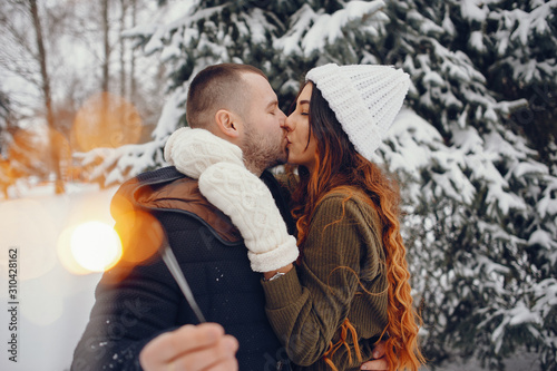 Pretty couple walking in a winter park. Man and woman have fun with snow