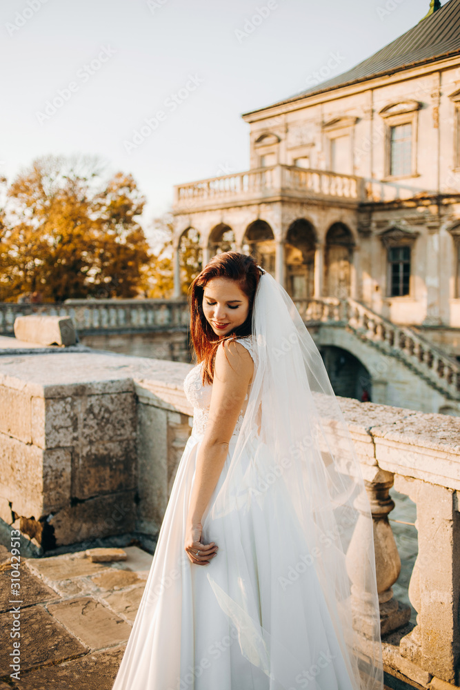 Fototapeta premium Pretty bride stands on the balcony of an old castle