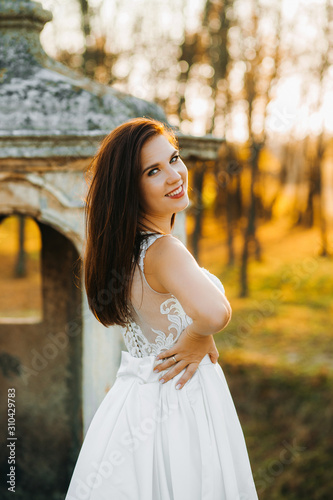 Pretty redheaded bride stands on the balcony of an old castle