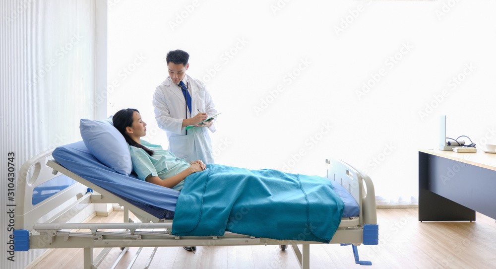 Asian Male Doctor Is Talking To Female Patients Lie In Bed In The Hospital Room About The 7903