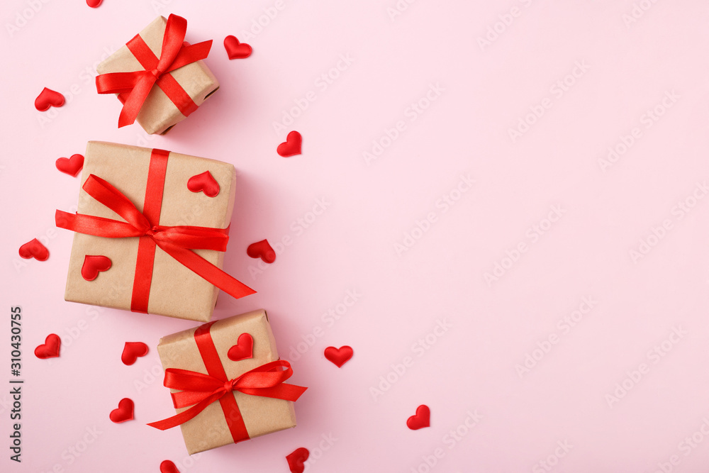 Presents with red bow on pink background with heart confetti. Flat lay style. Valentine day concept Presents with red bow on pink background with heart confetti. Flat lay style. Valentine day concept