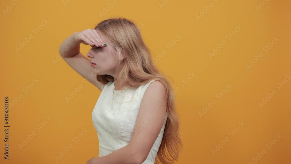 Disappointed caucasian young lady keeping hand on forehead, looking into distance over isolated orange background wearing white shirt. Lifestyle concept Disappointed caucasian young lady keeping hand on forehead, looking into distance over isolated orange background wearing white shirt. Lifestyle concept