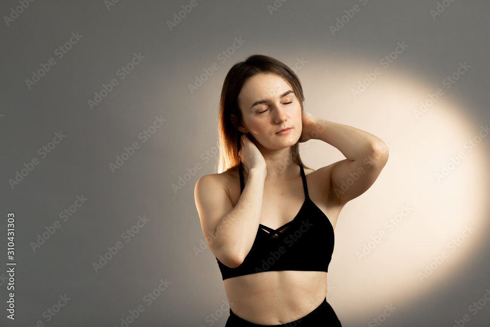 Athletic brunette girl in a black top kneading and doing exercises, on a gray background. Copy space Athletic brunette girl in a black top kneading and doing exercises, on a gray background. Copy space