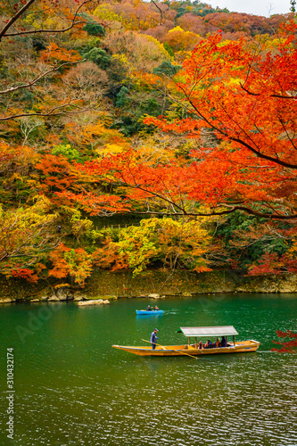 Boatman paddling the boat at Arashiyama forest view in the Autumn along Katsura river. Kyoto, Japan. © littlekop