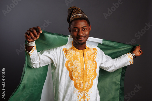 Successful african man winner before waving Nigeria flag Smiling and looking to the camera photo