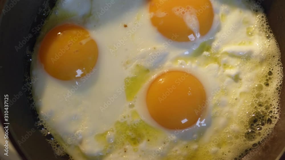 Egg omelette is being prepaired in a frying pan close up - Three yellow eggs in Eastern Europe Latvia Riga Egg omelette is being prepaired in a frying pan close up - Three yellow eggs in Eastern Europe Latvia Riga