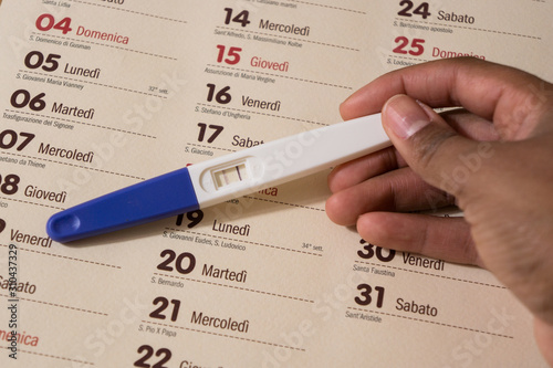 Woman holding a positive pregnancy test on a wooden desk