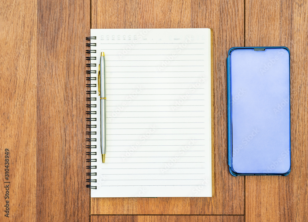 Top view image of open notebook with blank pages and cellphone on wooden table Top view image of open notebook with blank pages and cellphone on wooden table