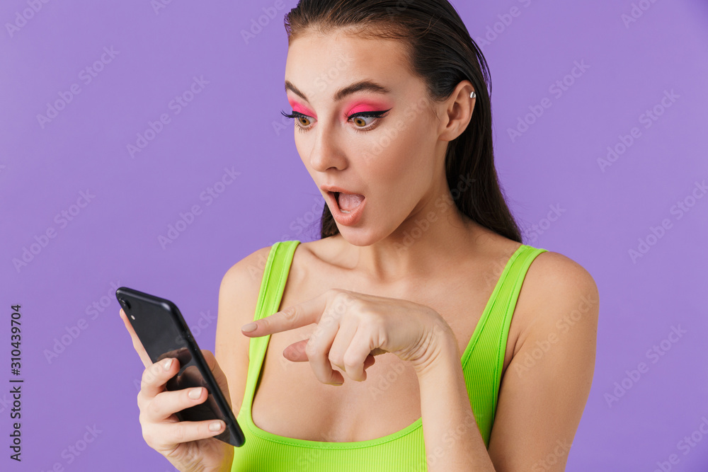 Photo of surprised young woman using and pointing finger at smartphone Photo of surprised young woman using and pointing finger at smartphone