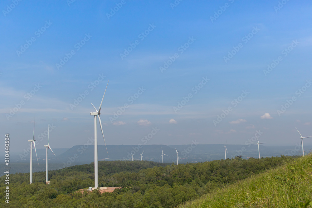 Mountain wind turbines for generating electricity Behind the mountains in the sky, there are white clouds on a sunny day.