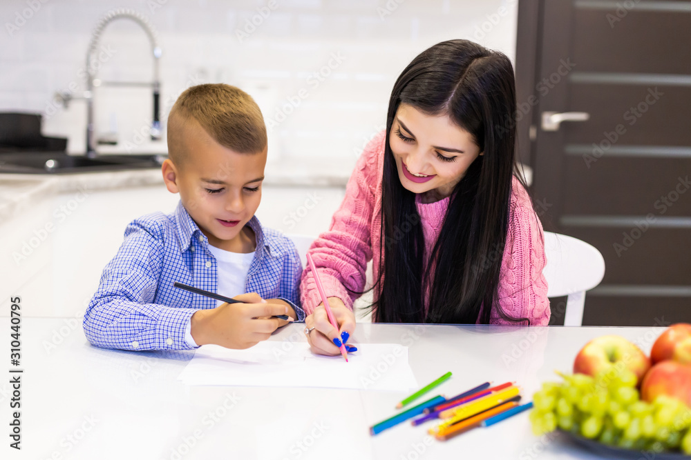 Happy mother and son drawing with color pencils is having fun at home Happy mother and son drawing with color pencils is having fun at home