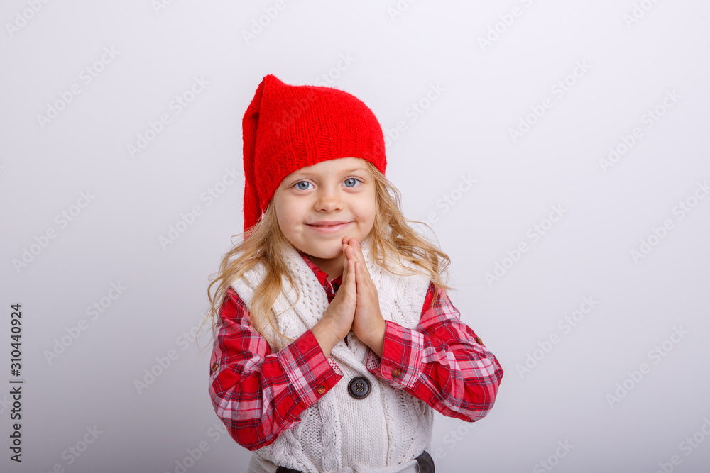 a smiling little girl in a Santa hat folded her hands in front of her, completely isolated on a white background a smiling little girl in a Santa hat folded her hands in front of her, completely isolated on a white background