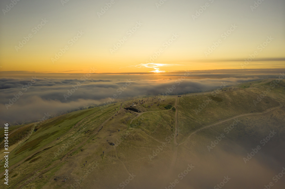 Spectacular Malvern Hills sunrise with low cloud and people walking