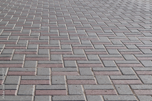 The surface of the pavement paved with paving stones of rectangular shape. The pavers are lined with a pattern. Tiles are gray and brown. Background or backdrop.