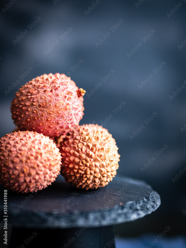 Frische Litschi auf einem grauen Podest, rustikaler Stil, exotische Frucht