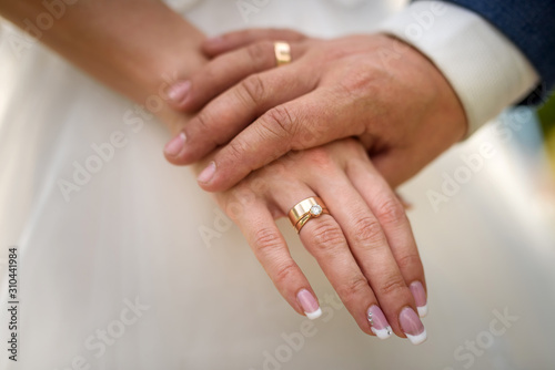 Parts of groom s and bride s hand holding each other. Wedding ceremony and celebration concept