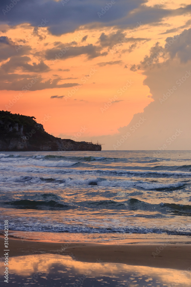 View of the bay of Peschici at sunset: sandy beach with on background, Italy (Puglia). Peschici is famous for its seaside resorts, its territory belongs to the Gargano National Park.