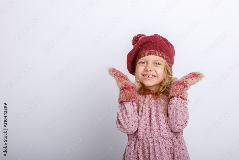 cute happy little girl in mittens, gloves and a winter hat on a white background