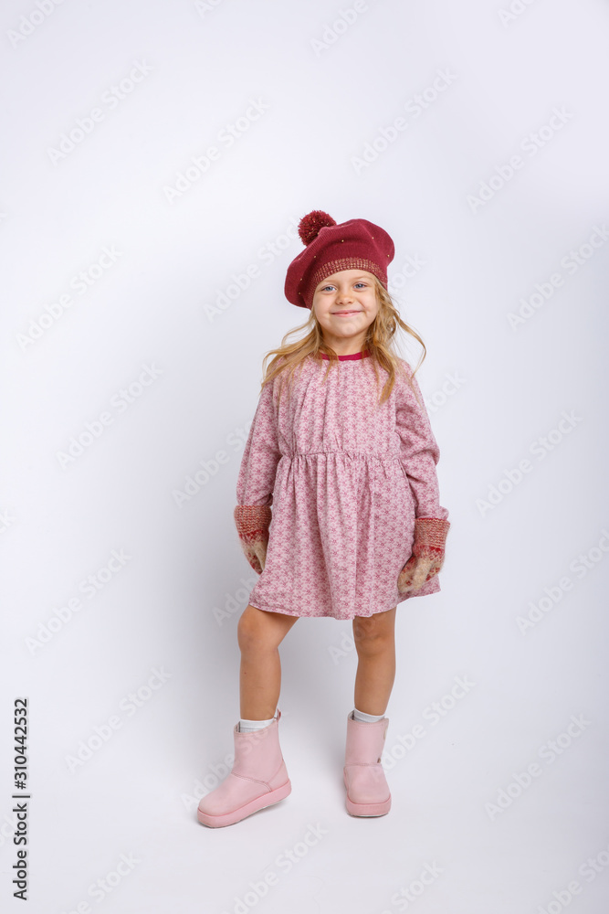 portrait of a small smiling girl in mittens and hat on a gray background portrait of a small smiling girl in mittens and hat on a gray background