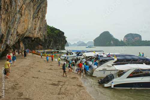 Mass landing of tourists on the wild beaches of Krabi Islands. A large number of people go from motor boats to the beach.
