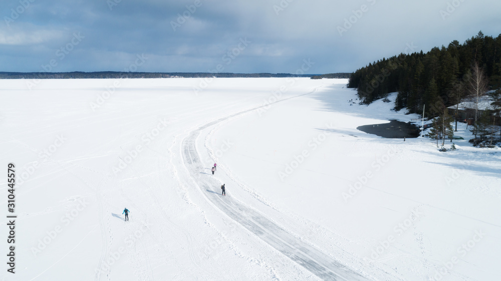Aerial view of frozen lake. Many ice skaters on the ice. Winter background concept.  People riding on a winter day. 
