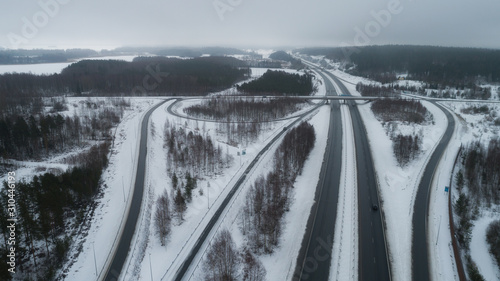 Aerial view of the road with road bridge and forest in winter on a cloudy day. Highway in Finland.