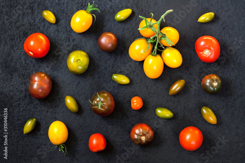 Assortment of colorful fresh tomatoes on black background