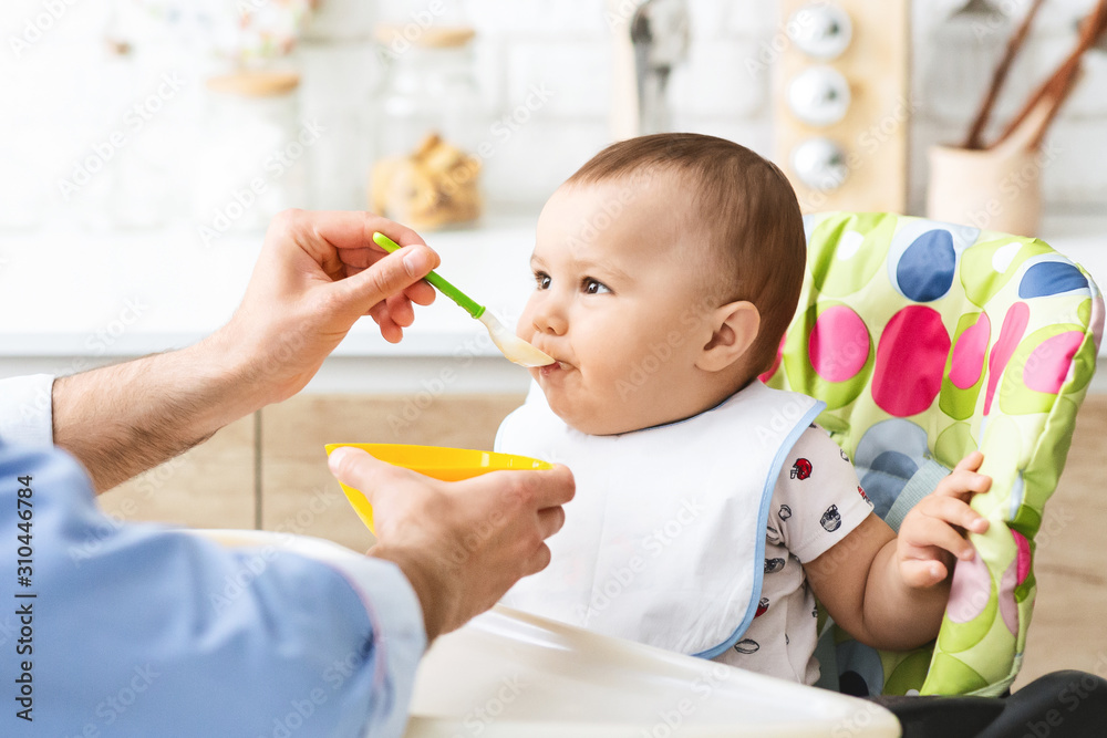 Toddler eating healthy kid food at kitchen interior Toddler eating healthy kid food at kitchen interior