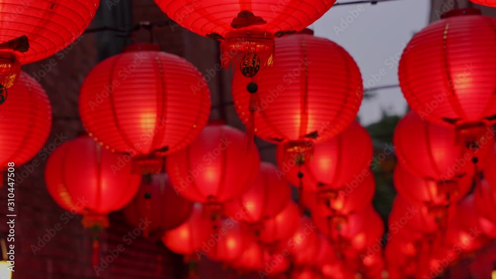 Walking on a Chinese traditional street at night with beautiful round red lantern hanging and swaying, concept of lunar new year festival, close up. The undering word means blessing.