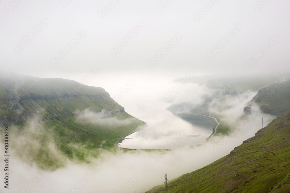 Obraz premium Incredible picture of weather on Faroe Islands in summer with thick fog around a fjord.