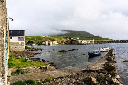 Nolsoy island harbor with boats and small houses  Nollywood sign on a hill. Faroe Islands  Denmark.