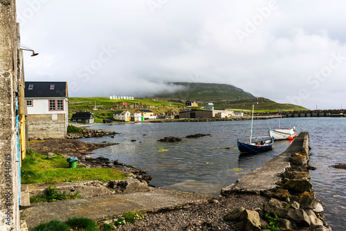 Nolsoy island harbor with boats and small houses, Nollywood sign on a hill. Faroe Islands, Denmark. photo