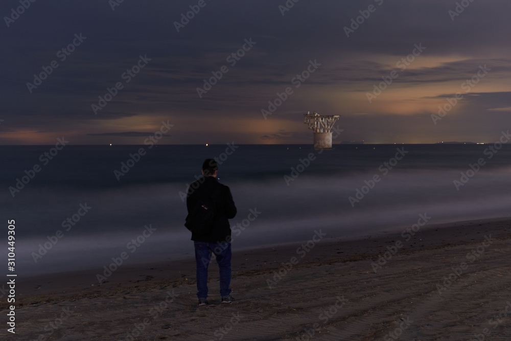 Fototapeta premium Man looking at mine tower from beach