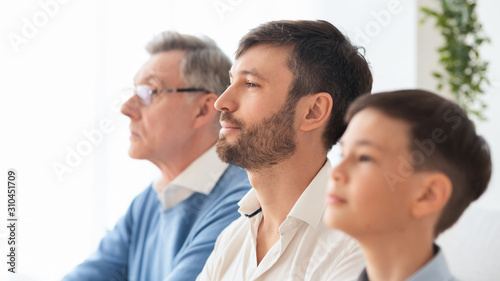 Mature man sitting between elderly father and little son indoor