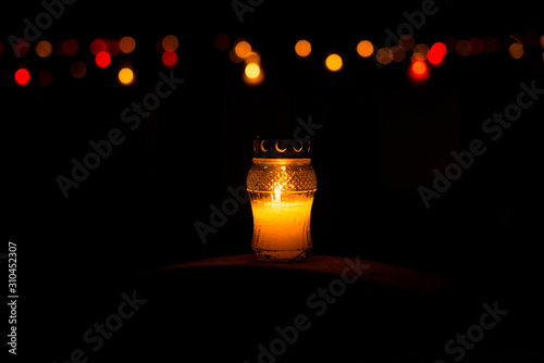 Candle snitch on the tombstone, the feast of the dead, All Saints' Day by night with bokeh colorful background. Copy space photo