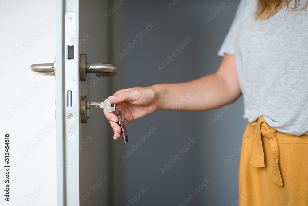 Woman hands opening a door with keys. Close up. Hand unlocks key lock
