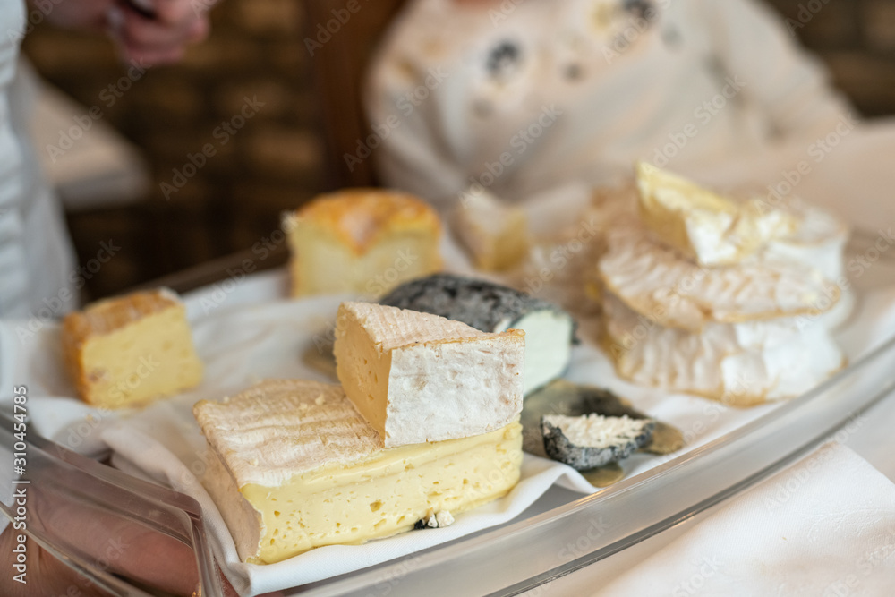 The waiter holds a plate with the Normandy cheeses