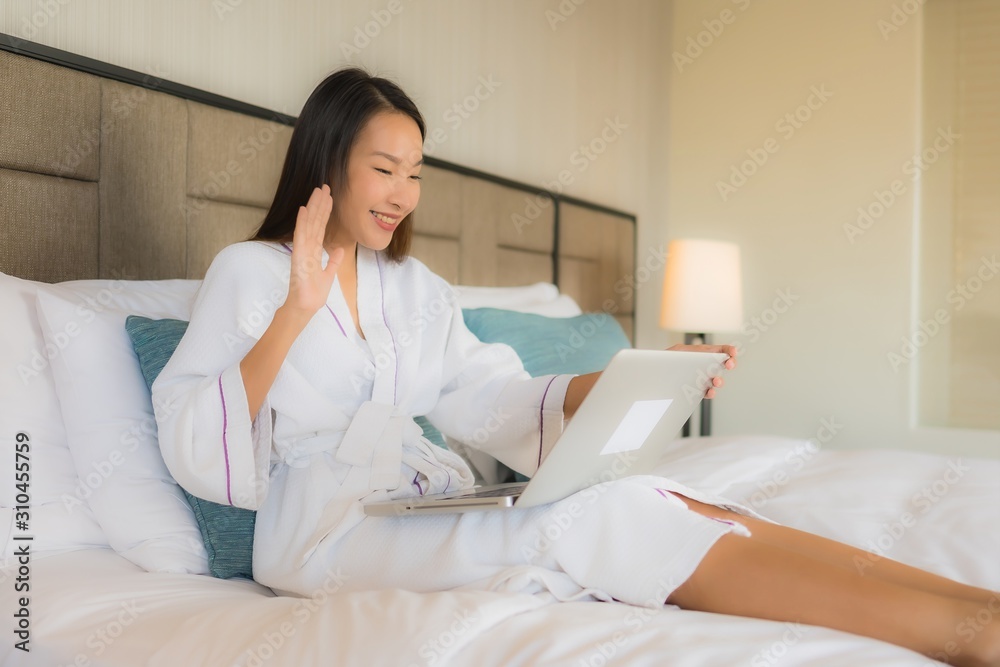 Portrait beautiful young asian women using laptop or computer with mobile smart phone on bed Portrait beautiful young asian women using laptop or computer with mobile smart phone on bed