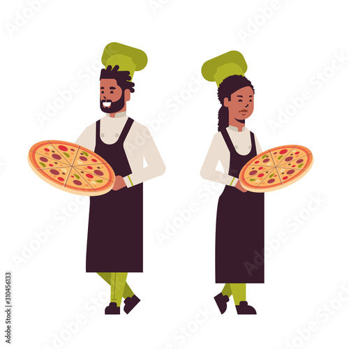 cooks couple professional chefs holding trays with fresh pizza african american man woman restaurant kitchen workers in uniform standing together cooking food concept flat full length vector