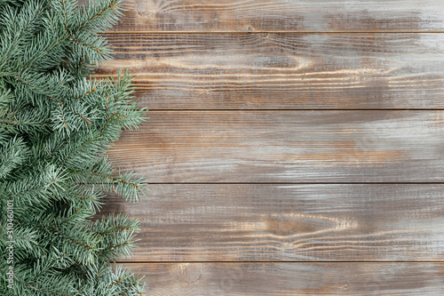 Christmas border with fir branches on a wooden background.