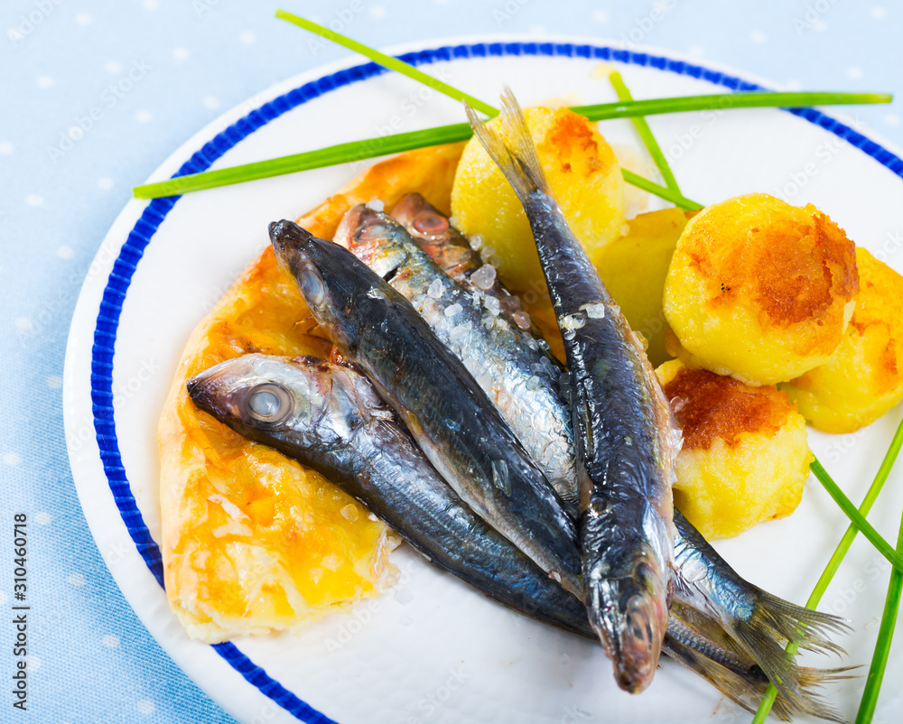 Dish of tasty fried anchovy with potato croquettes and cake served
