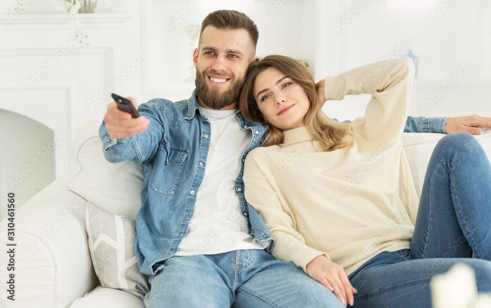 Smiling young couple watching TV and relaxing at home Smiling young couple watching TV and relaxing at home