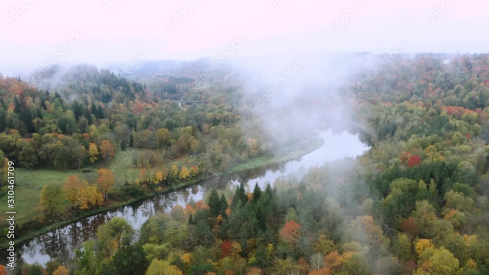 Valley of colorful trees and river covered in fog. Misty autumn morning in Sigulda, 4k drone video Valley of colorful trees and river covered in fog. Misty autumn morning in Sigulda, 4k drone video